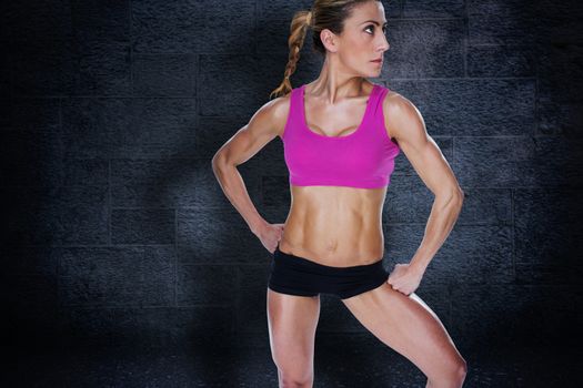 Female bodybuilder posing in sports bra and shorts against black background