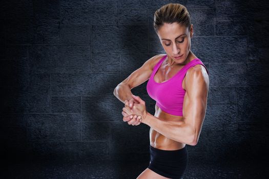 Female bodybuilder flexing in pink sports bra against black background