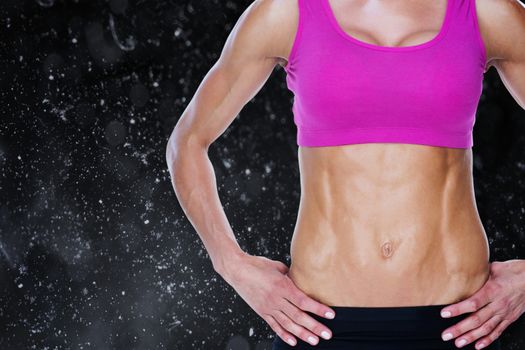 Female bodybuilder posing with hands on hips mid section against black background