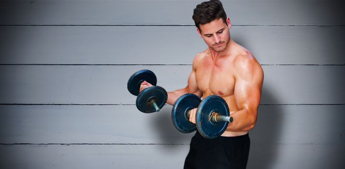 Bodybuilder lifting dumbbell against painted blue wooden planks