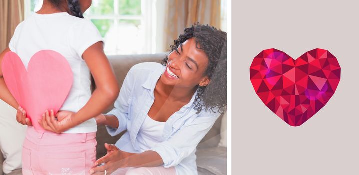 heart against pretty mother sitting on couch with daughter hiding heart card