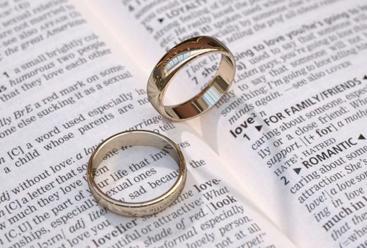 Wedding rings on a dictionary page showing love definition,  close up