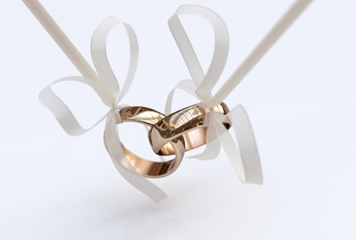 Couple of gold wedding rings with bows on white background