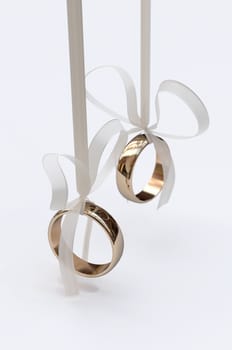 Couple of gold wedding rings with bows on white background