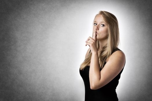 Blond woman with a finger to his lips to indicate to be quiet