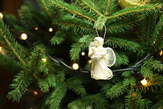 Christmas angel on christmas tree branch, lights hanging in a tree 