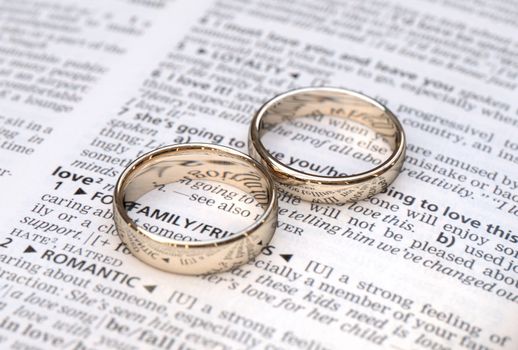 Wedding rings on a dictionary page showing love definition,  close up