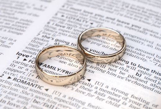 Wedding rings on a dictionary page showing love definition,  close up