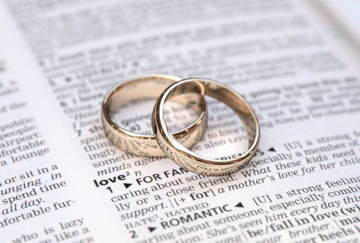 Wedding rings on a dictionary page showing love definition,  close up