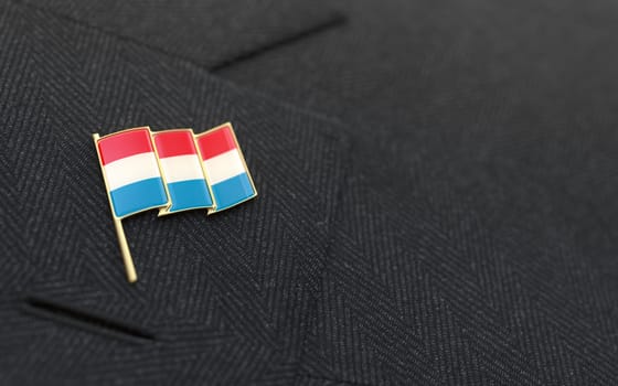 Luxembourg flag lapel pin on the collar of a business suit jacket shows patriotism