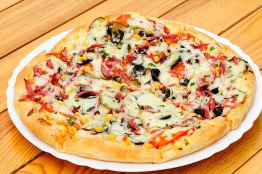 Whole pizza with cut pepperoni, black olives, corn, cheese and pickled cucumbers