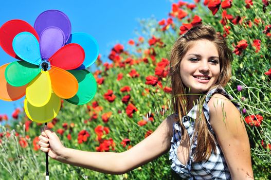 happy cute teen girl having fun with windmill on the poppy field 
