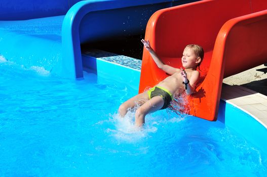 Cute little boy sliding down a water slide