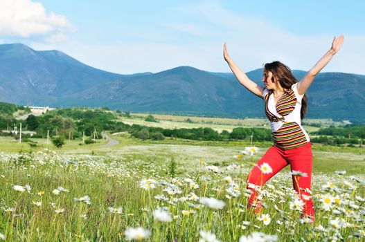 Young teen girl doing a cartwheel on daisy meadow 