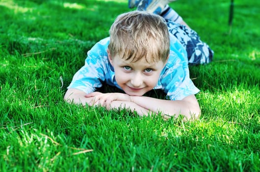 little blonde  boy laying on the sunny meadow 