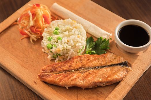 Grilled salmon with rice and vegetables at wooden table