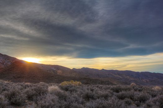 The sun sinking below the hills of the desert.