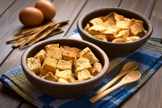 Two rustic bowls of bread pudding made of diced stale bread, milk, egg, cinnamon, sugar and butter, photographed with natural light (Selective Focus, Focus one third into the first bread pudding)