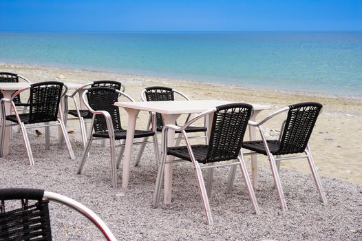 Beach cafe with empty tables and chairs placed at the sea waterfront