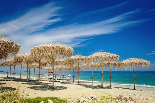 Rows of reed umbrellas on the sea beach 