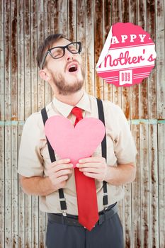 Geeky hipster crying and holding heart card against wooden planks