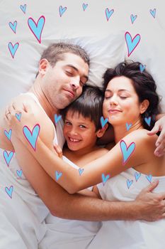 Happy family lying in bed  against red hearts