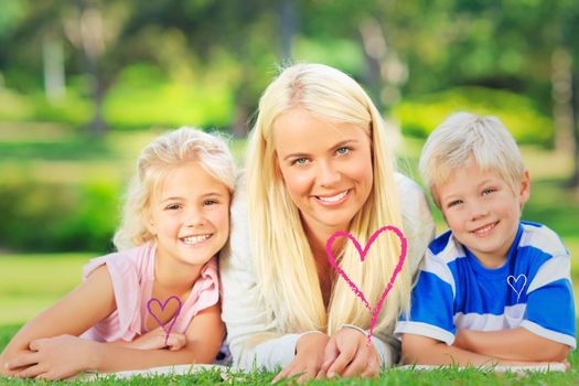 Mother with her children lying down during the summer against valentines love hearts