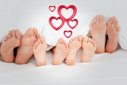  Family on the bed at home with their feet showing against pink hearts