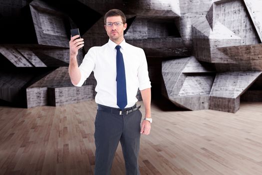 Serious businessman holding his phone against abstract room