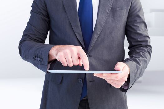 Businessman using his tablet pc  against abstract white design