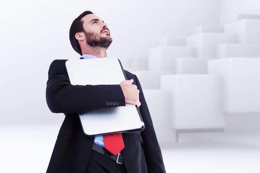 Concentrating businessman in suit holding laptop against abstract white design