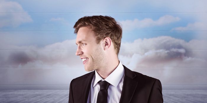 Young handsome businessman looking away against clouds in a room