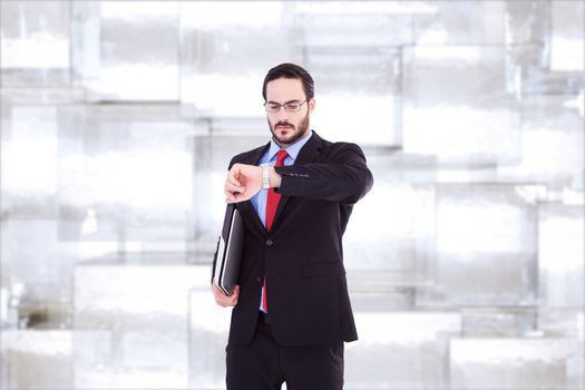 Frowning young businessman checking time against abstract background