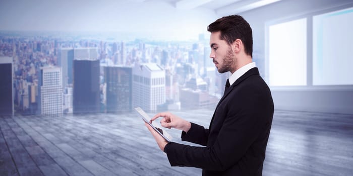 Concentrated businessman touching his tablet against city scene in a room