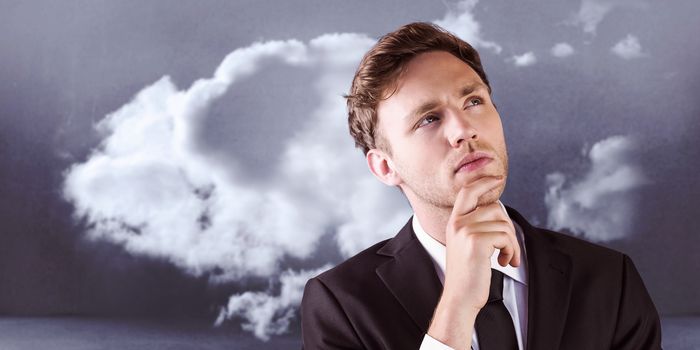 Young businessman thinking with hand on chin against clouds in a room