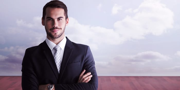 Smiling businessman posing with arms crossed against clouds in a room