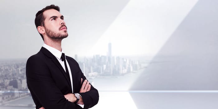 Thinking businessman with his arms crossed against city scene in a room