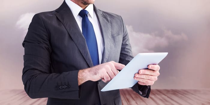 Businessman using his tablet pc  against clouds in a room