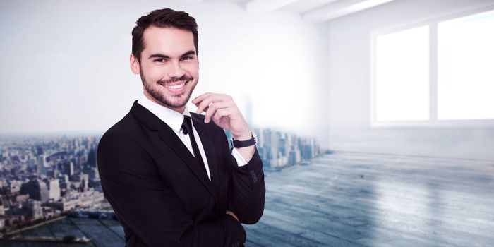 Stylish businessman smiling at camera against city scene in a room