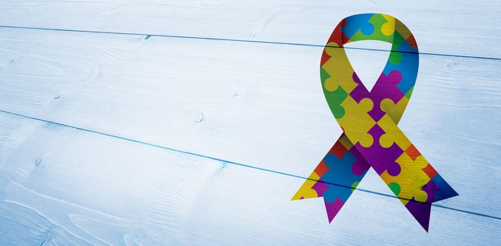 Autism awareness ribbon against bleached wooden planks background
