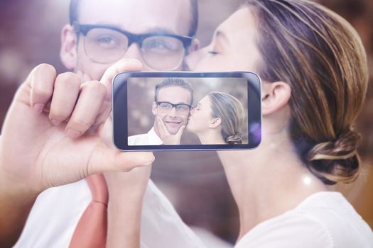 Hand holding smartphone showing against young woman kissing man