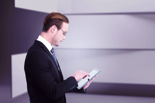 Businessman in reading glasses using his tablet pc  against abstract room