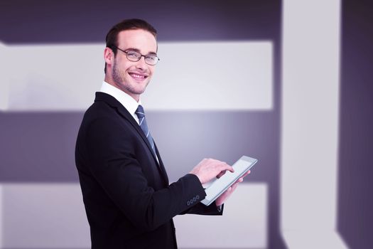 Happy businessman using his tablet pc  against abstract room