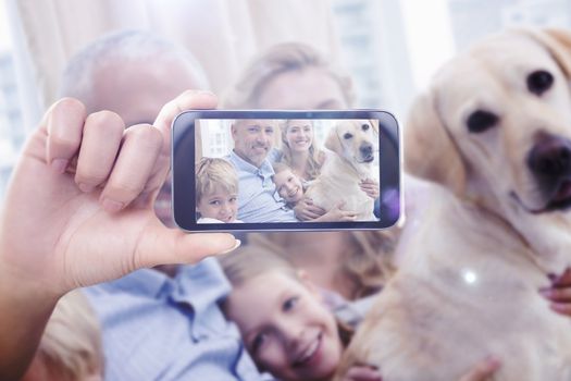 Hand holding smartphone showing against parents and their children on sofa with labrador