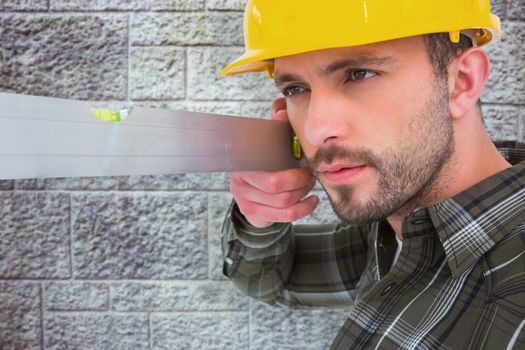 Carpenter using spirit level  against grey brick wall