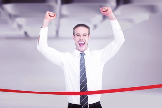 Businessman crossing the finish line and cheering against white abstract room