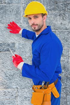 Handyman holding spanner against grey