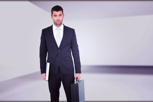 Businessman standing with his briefcase and documents against abstract room