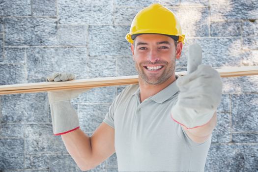 Worker with plank of wood against grey