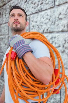 Repairman holding wire roll against grey brick wall